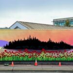 photo shows a mural of a sunset behind halket island, with poppies growing in the foreground, a piper playing to the sunset, and an indigenous moon spirit